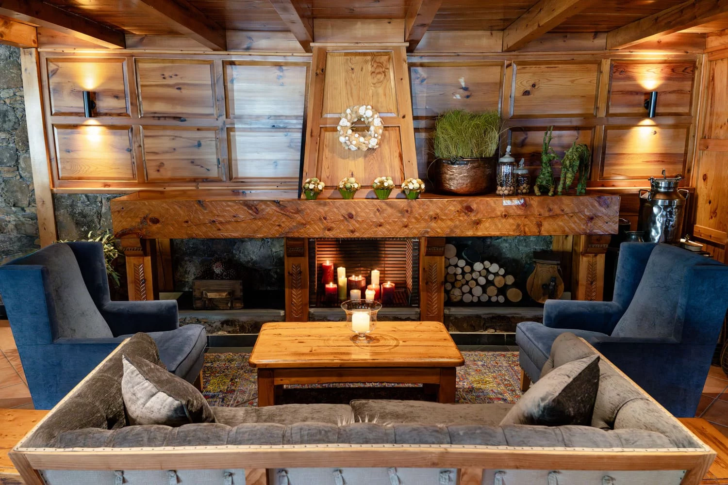 Salón con chimenea de piedra, velas y sillones, Hotel Xalet Montana, Soldeu